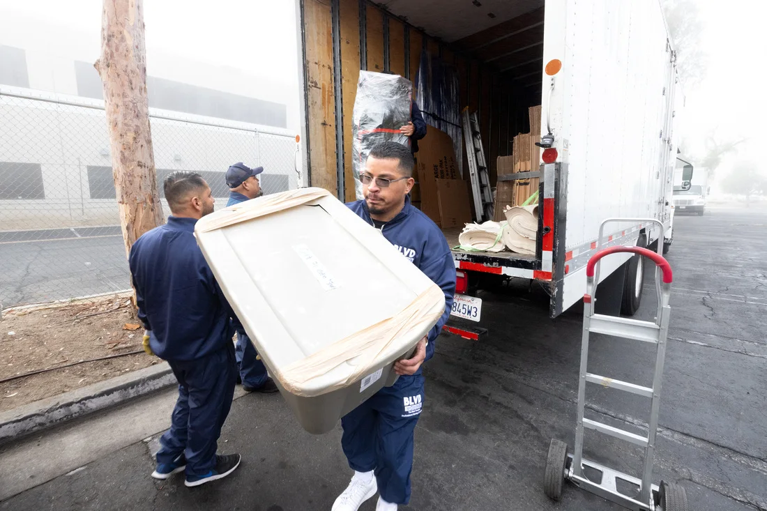 BLVD movers carrying a protected household storage bin to the truck