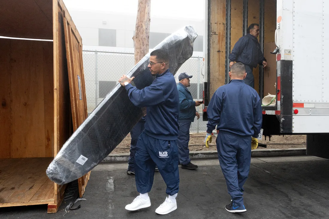 BLVD movers carefully carrying a protected flat-screen television