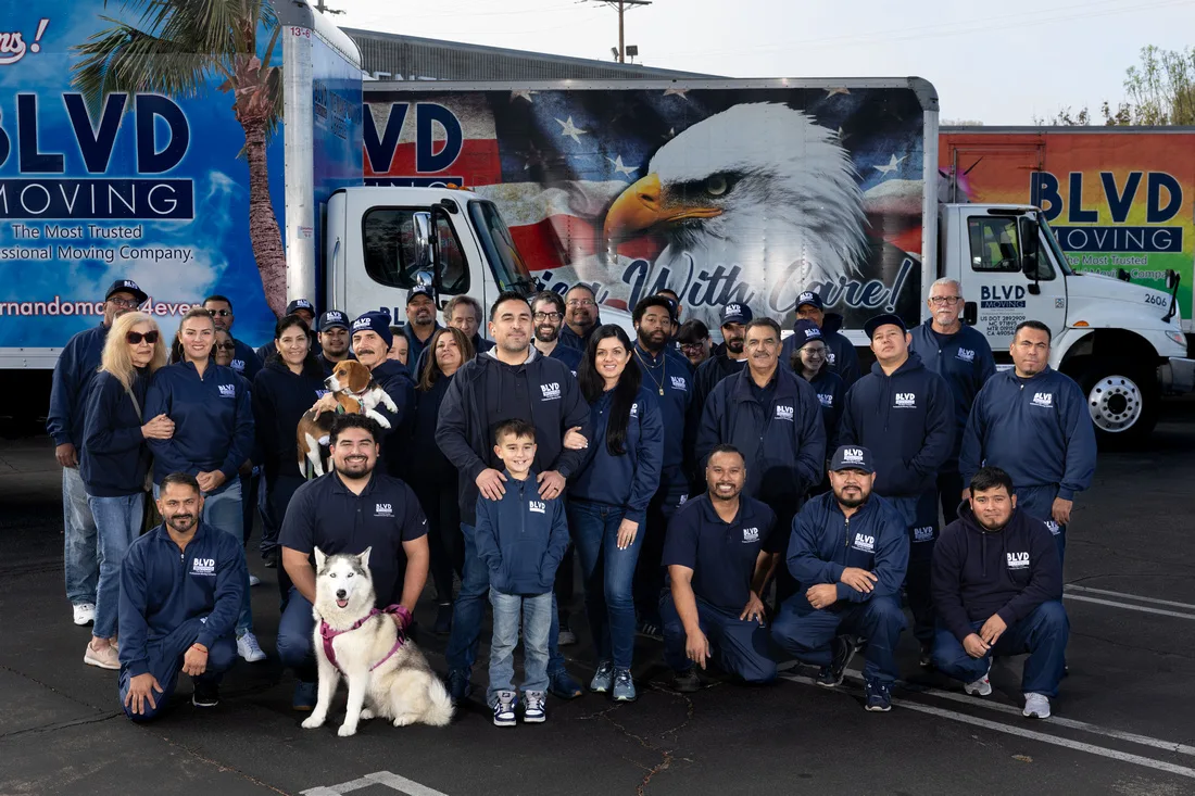 BLVD Moving team assembled in front of branded moving trucks