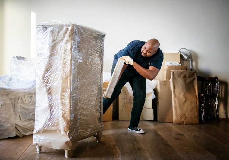 Photo of a mover wrapping a wardrobe/cabinet to get it ready for moving